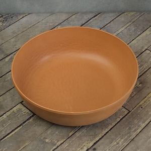 May include: A round, terracotta-colored bowl with a textured surface. The bowl has a wide, shallow design and is suitable for serving food. The bowl is made of a durable material and is ideal for everyday use.