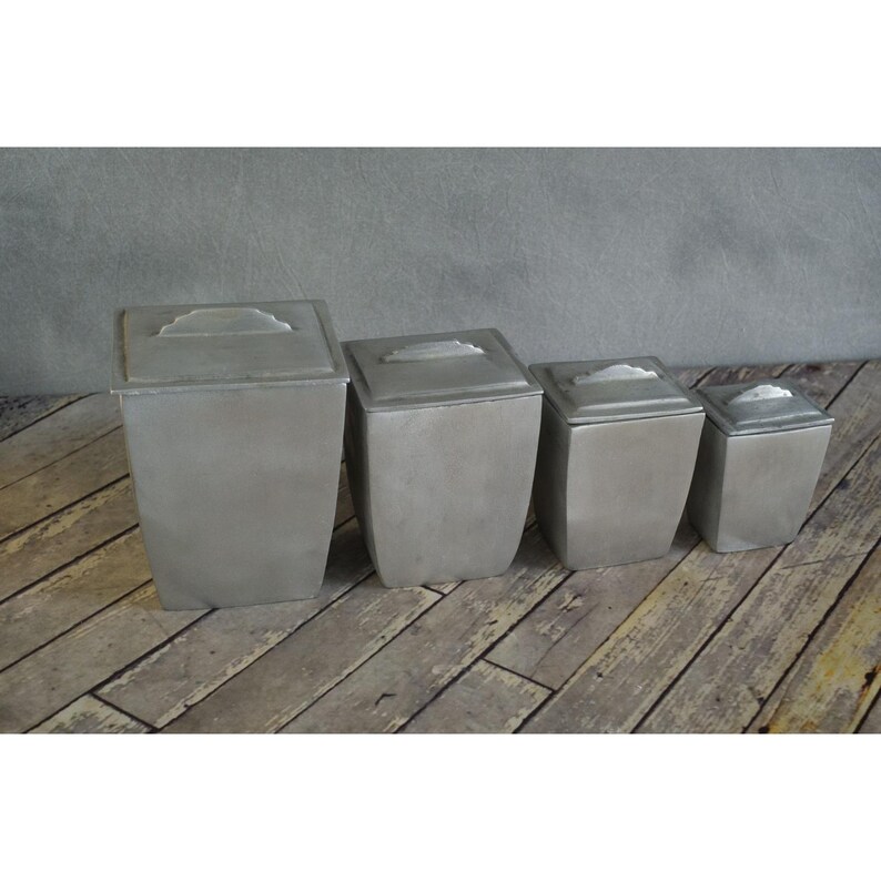 May include: A set of three ceramic mugs with a speckled, matte finish in cream, light grey, and dark grey. Each mug has a simple, minimalist design, suitable for coffee or tea.