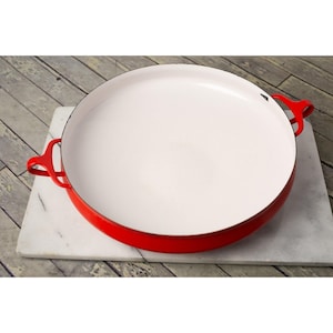 May include: A red enamel cast iron baking dish with two handles. The dish is empty and has a white interior.