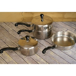 May include: A set of three stainless steel pots with black handles. The largest pot has a lid and is a double boiler. The other two pots are smaller and have lids.