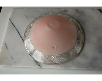 May include: A pink glass ceiling light fixture with a silver decorative border. The light fixture has a textured, ribbed surface.
