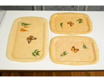 May include: Three rectangular trays with a light beige background and a raised edge. Each tray features a different butterfly design with brown, orange, and yellow wings. The butterflies are surrounded by green leaves.