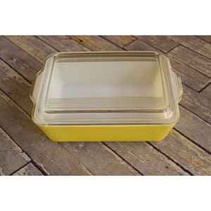 May include: A yellow glass baking dish with a clear glass lid. The dish has a rectangular shape and rounded corners.