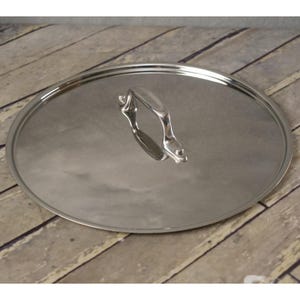 May include: A stainless steel pot lid with a handle. The lid is round and reflective, with a polished finish. The handle is curved and attached to the center of the lid.