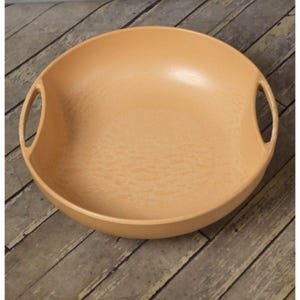 May include: A peach-colored serving bowl with two integrated handles. The bowl has a wide, shallow design and a textured surface. The handles are rounded and seamlessly integrated into the bowl's rim. The bowl is made of a durable material.