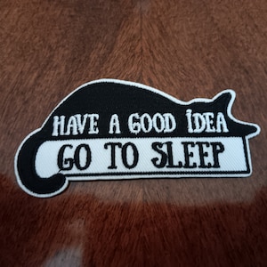 May include: Black and white embroidered iron-on patch with a sleeping cat and the text "Have a good idea, go to sleep."