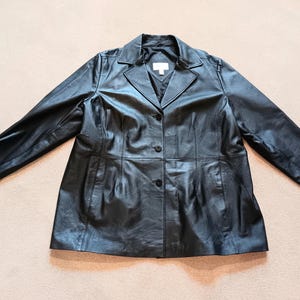 May include: A black leather jacket with a collar, three buttons, and long sleeves.