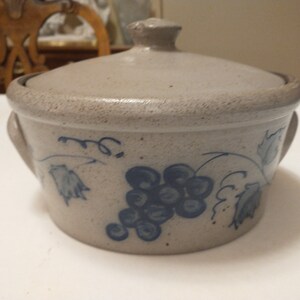May include: A gray stoneware casserole dish with a lid, featuring a blue and white grapevine design.
