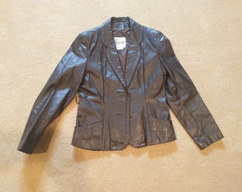 May include: A brown leather blazer with a single button closure and two pockets. The blazer has a  "Renowned" label on the inside.