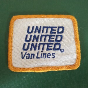 May include: A white fabric patch with an orange border. The patch has the text "UNITED UNITED UNITED Van Lines" embroidered in blue thread.