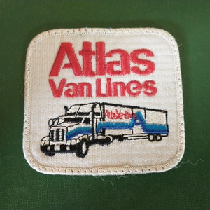 May include: Embroidered patch featuring the words "Atlas Van Lines" in red, above a detailed illustration of a semi-truck and trailer. The truck is white with blue accents, and the patch has a white background and a stitched border.