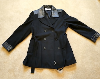May include: A black double-breasted coat with a black leather collar and cuffs. The coat has a belt and four buttons.