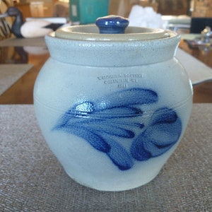 May include: A blue and white ceramic crock with a blue lid. The crock has a blue floral design and the text "Wisconsin Pottery, County of WI, 1913" on the side.