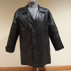 May include: A black leather coat with a classic design. The coat features a notched collar, button closures, and long sleeves with buttoned cuffs. The coat is displayed on a mannequin.