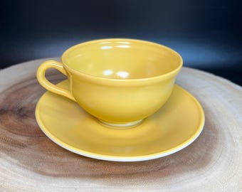 Könnte beinhalten: Ein gelbes Tee-Set aus Tasse und Untertasse. Tasse und Untertasse sind beide einfarbig gelb.