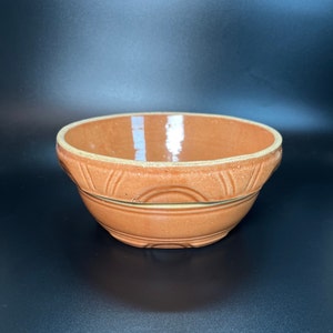 Puede incluir: Un tazón mezclador de cerámica de color terracota con un borde decorativo y un interior ligeramente esmaltado.