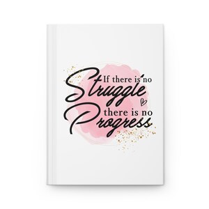May include: A white journal with a pink watercolour background and gold glitter. The text on the journal reads "If there is no struggle there is no progress".