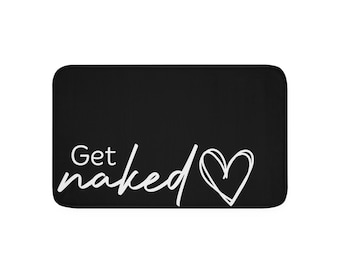 Puede incluir: Alfombra de baño rectangular negra con las palabras "Get naked" en escritura blanca y un contorno de corazón blanco. La alfombra tiene esquinas redondeadas y un fondo negro liso.