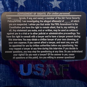 May include: A black card with white text outlining the rights of a civilian personnel member being questioned by the Air Force Security Police. The card includes the text "ADVISEMENT OF RIGHTS (For civilian personnel)" and "USAF" at the bottom.