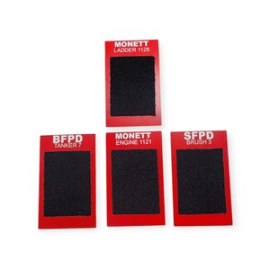 May include: Five red rectangular patches with black fabric squares in the center. The patches have white text that reads "BFPD Tanker 7", "MONETT Engine 1121", "SFPD Brush 3", and "MONETT Ladder 1128".