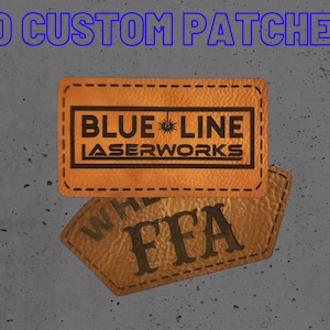May include: Two brown leather patches with stitched edges. The top patch has the text "BLUE LINE LASERWORKS" in black lettering. The bottom patch has the text "FFA" in black lettering.