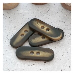 May include: Four brown and beige oval buttons with two holes each. The buttons have a marbled effect.