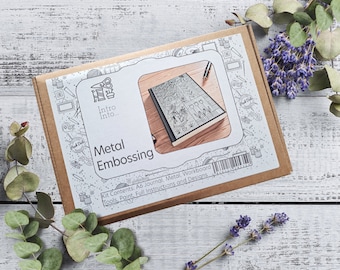 Puede incluir: Una caja marrón con una etiqueta blanca que dice "Intro Into... Metal Embossing". La etiqueta tiene una ilustración en blanco y negro de un diario con un bolígrafo y las palabras "Kit Contents: A6 Journal, Metal, Workboard Tools, Paint, Full Instructions and Designs".