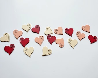 May include: Assortment of wooden heart-shaped ornaments in various shades of red, pink, and cream. Each heart features a decorative swirl design.