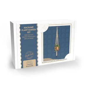 May include: A white box displaying a macramé plant hanger kit. The kit contains materials to create a natural cotton plant pot hanger. The box has text that reads "MACRAMÉ PLANT HANGER KIT" and "Make your own beautiful natural cotton plant pot hanger."