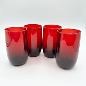 May include: Four stemless drinking glasses with a deep red hue. The glasses have a rounded shape and a gradient color, transitioning from red at the top to a darker shade at the base. The glasses are made of glass and are suitable for water, juice, or other beverages.
