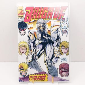 May include: Comic book cover for "Brigade" #1, featuring a muscular, silver-haired character in a futuristic suit. The title is in large, red and yellow letters. Surrounding the main figure are several character portraits. The cover includes the text "W'IN THIS COVER!"
