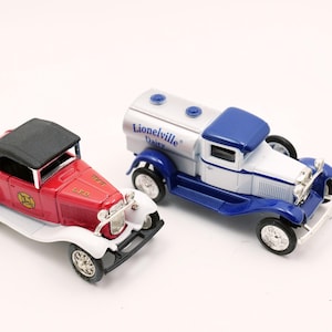 May include: Two vintage toy cars. One is a red convertible with a black top and white accents, with "LFD" text. The other is a blue and white tanker truck with "Lionelville Dairy" text. Both have chrome details and black tires.