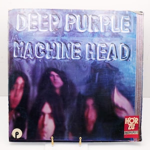 May include: Deep Purple's "Machine Head" album cover. The album art features the band members with the album title in a neon-style font. The background is a mix of purple and blue.