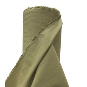 May include: A roll of olive green fabric with a raw edge. The fabric is folded over and the raw edge is visible.