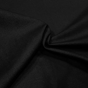 May include: Black fabric with a smooth, textured surface. The fabric is folded and draped, creating soft folds and curves.