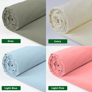 May include: Four rolls of fabric in various colors: grey, ivory, light blue, and light pink. Each roll is tightly wound, displaying the fabric's texture. Color labels are present below each roll.