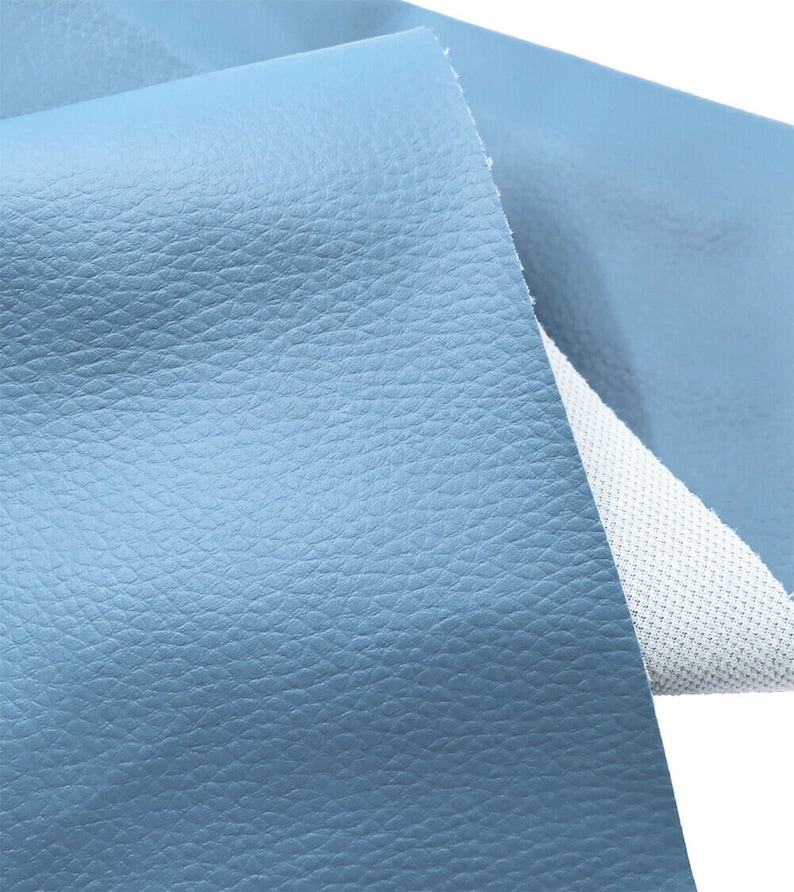 May include: A close-up of a light blue textured fabric. The fabric has a smooth, leather-like finish.