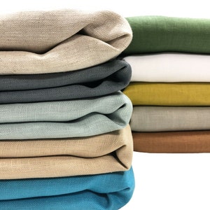 Peut inclure: Une pile de tissu plié en différentes couleurs, dont le beige, le vert, le blanc, le jaune, le gris, le bleu et le marron. Le tissu est disposé en une pile soignée, avec la couche supérieure pliée.