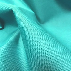 May include: Close-up of a turquoise fabric with a textured surface.