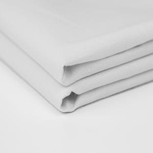 May include: A stack of three white fabric napkins folded neatly.
