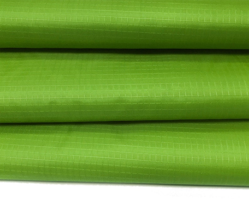 May include: Close-up of a green fabric with a grid pattern. The fabric is folded in thirds, showing the texture and weave.