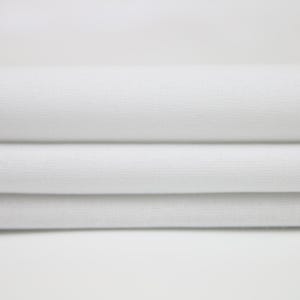 May include: White fabric folded in three layers, showing the texture of the material.