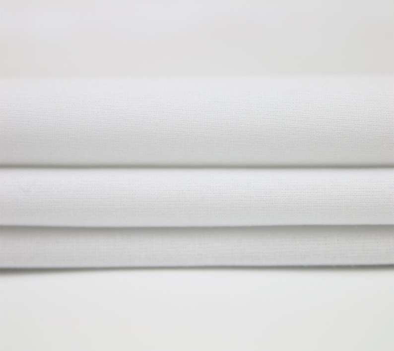 May include: White fabric folded in three layers, showing the texture of the material.