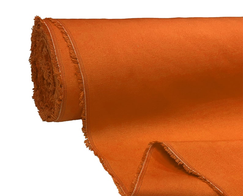 May include: A roll of orange fabric with a fringed edge. The fabric is rolled up and the end is unfurled, showing the texture of the material.