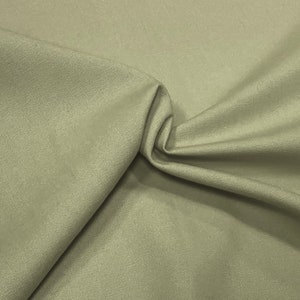 May include: A close-up of a light beige fabric with a subtle texture. The fabric is folded and draped, showcasing its soft and smooth surface.