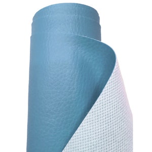 May include: A roll of blue upholstery fabric with a textured surface. The fabric is rolled up and the back side is visible, showing a white mesh backing.