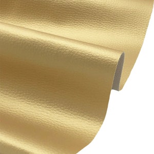 May include: A close-up of a gold-coloured faux leather fabric with a textured surface.