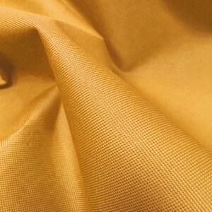 May include: Close-up of a yellow fabric with a textured surface. The fabric is folded and has a soft, smooth feel.