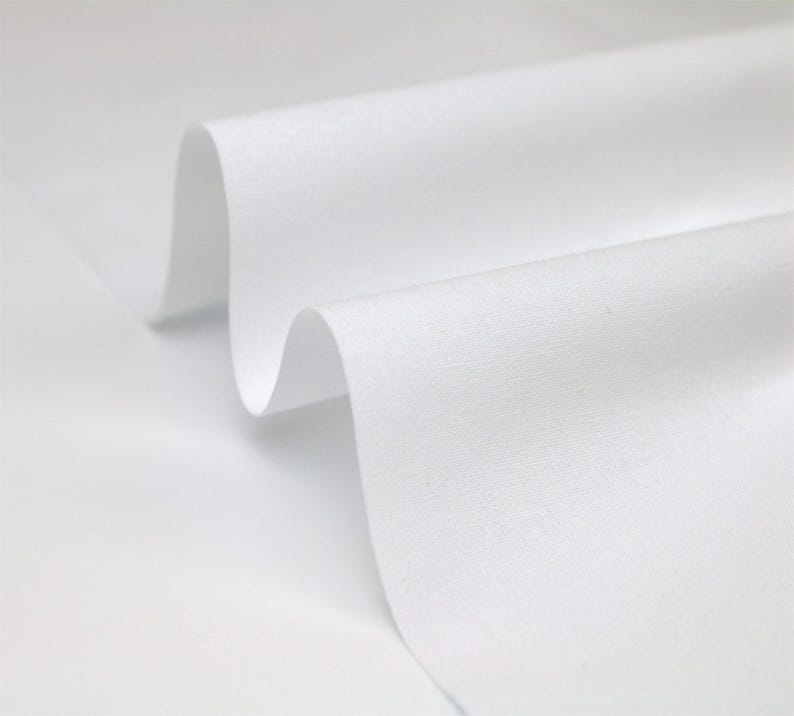 May include: White fabric with a smooth texture, folded in a wave-like pattern. The fabric is soft and appears to be lightweight.