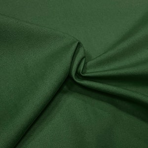 May include: A close-up of a dark green fabric with a smooth, even texture. The fabric is folded in a way that shows its drape and softness.